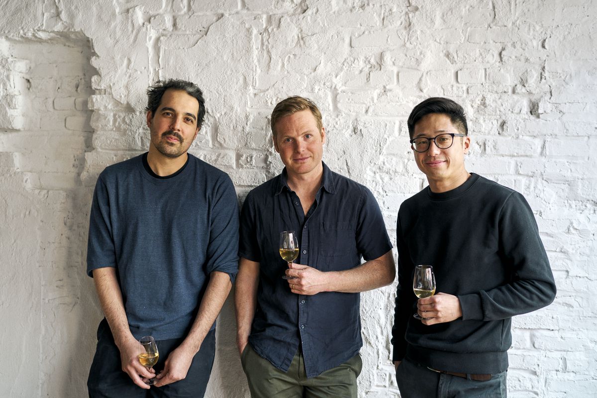 Three men — Nico Russell, Piper Kristensen, and Steve Wong — pose for a photograph holding glasses of wine.