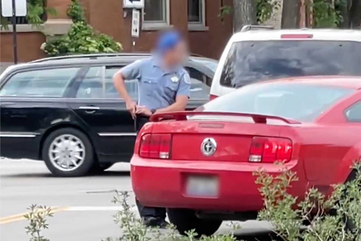 A Chicago police officer holsters his weapon after being involved in an apparent road rage incident in Logan Square.