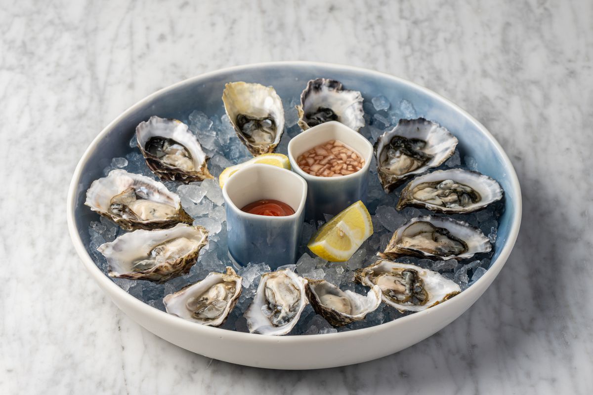 An array of fresh oysters over ice with mignonette sauce.