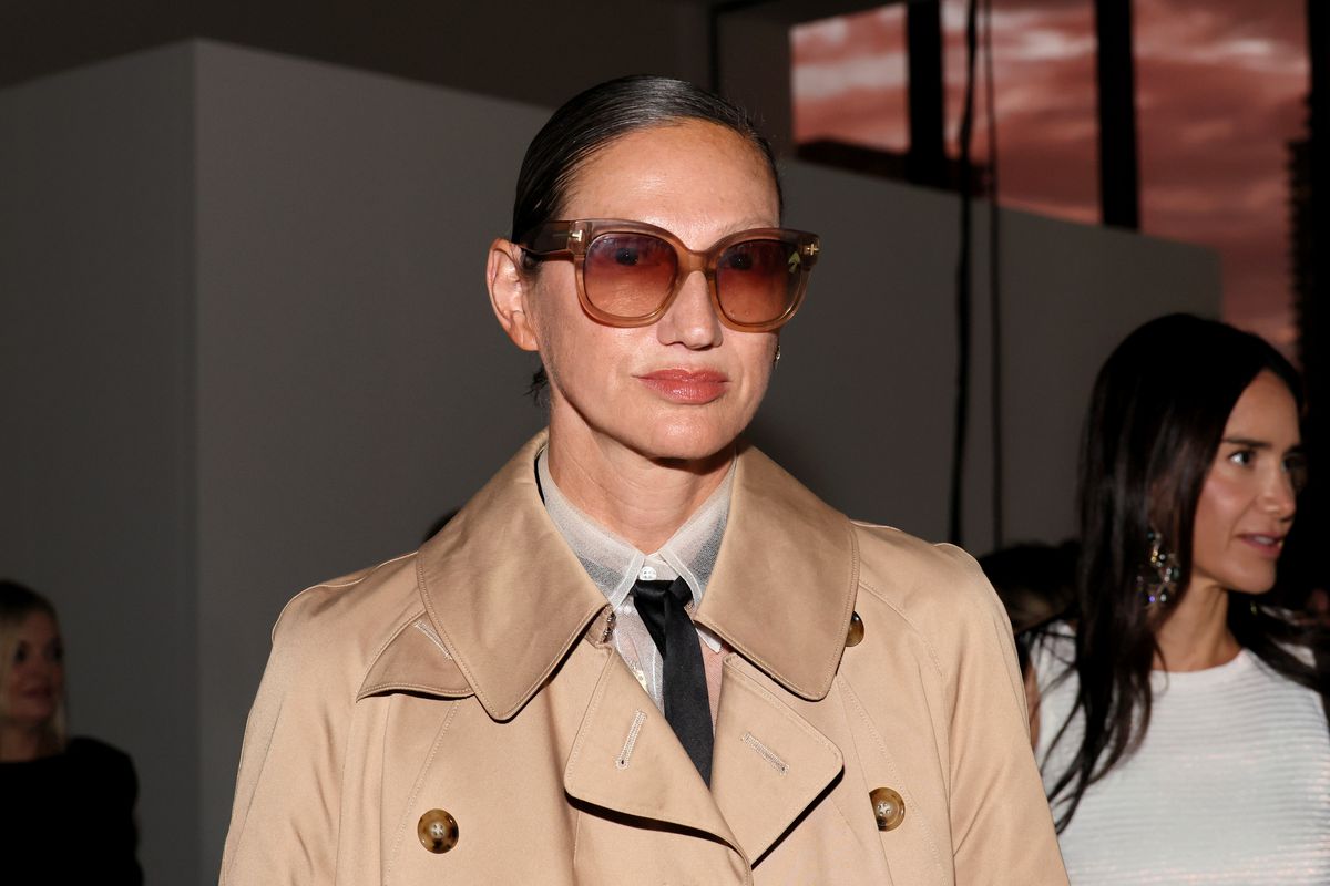 A woman in a trench coat and large dark glasses.
