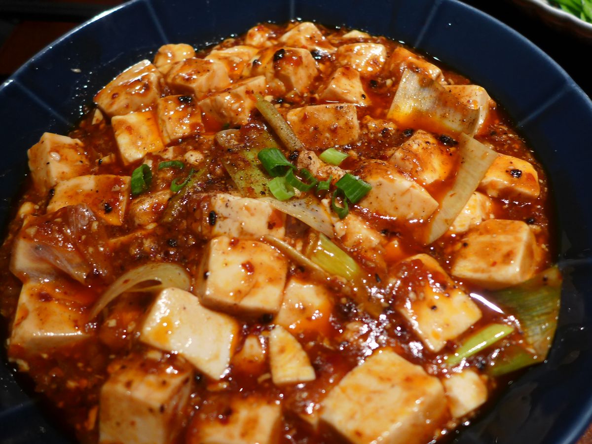 A bowl of dark red with powdery Sichuan peppercorns on top.