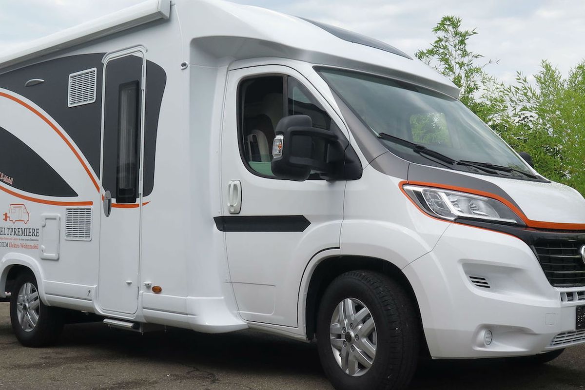 A white motorhome with black windows, black swoops on the side, and orange accent colors. 