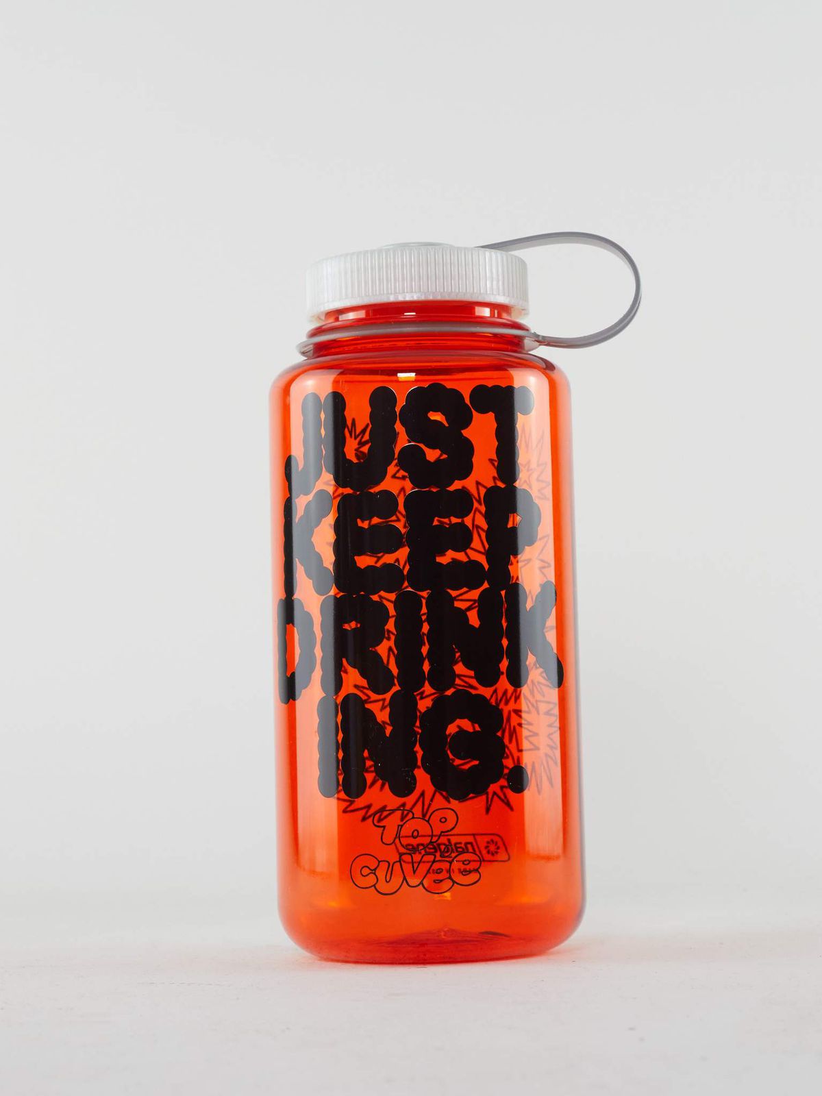 An orange Nalgene water bottle with “Just keep drinking” in black cartoon font