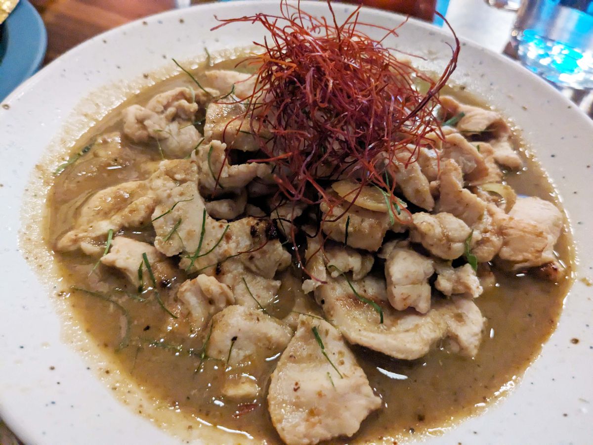 A heap of chicken pieces in a sauce of olive drab.