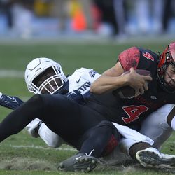 Utah State defensive tackle Marcus Moore, left, tackles San Diego State quarterback Jordon Brookshire (4) in the second half during an NCAA college football game for the Mountain West Conference Championship, Saturday, Dec. 4, 2021, in Carson, Calif.