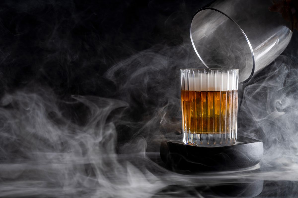A cocktail under a cloche of smoke.