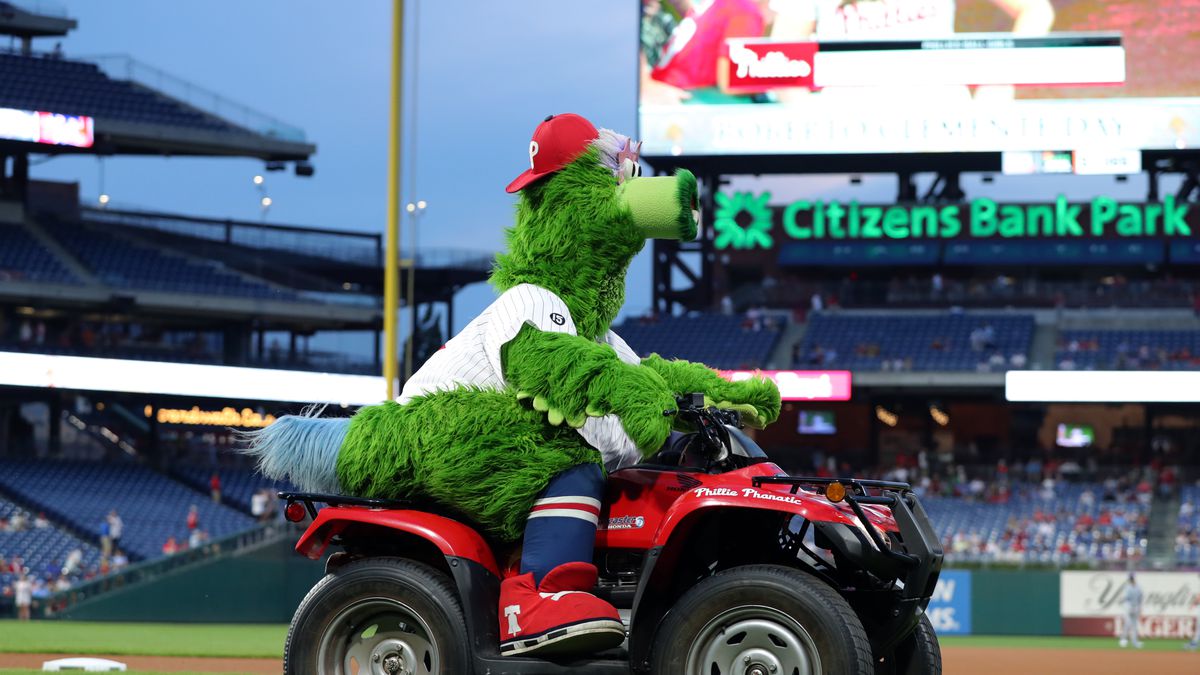 the Phillies mascot, a large, furry green bird called the phanatic, drives a four-wheeler on the field at citizens bank park in philly