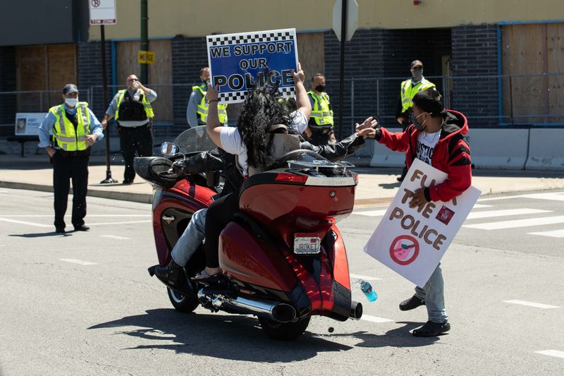 A protester splashes police supporters who were taunting and flipping off protesters with juice in front of the Jefferson Park district police station Saturday.