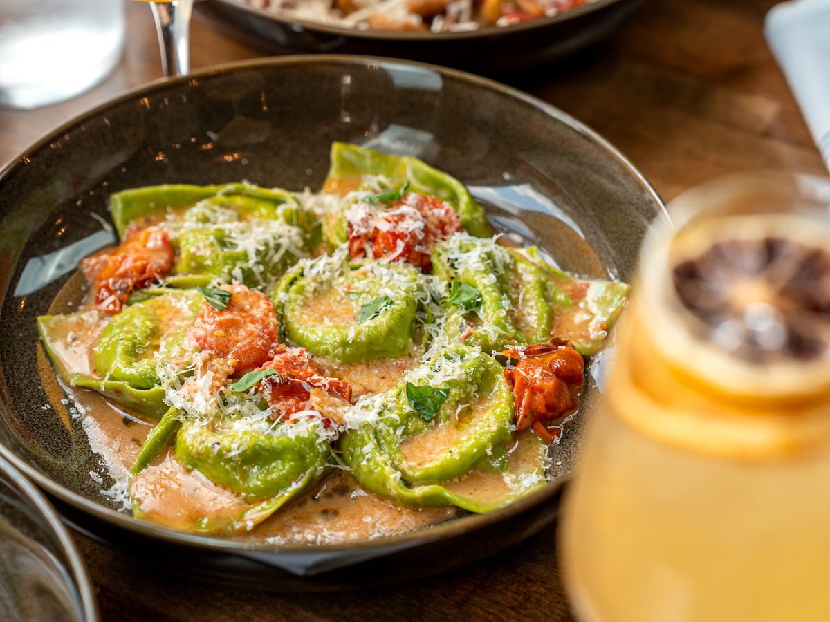 tortellini on a white plate with green sauce.