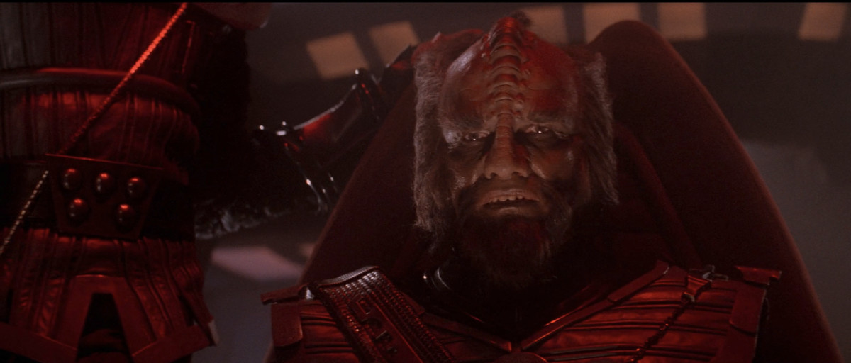 A Klingon commander sits and looks at something in red light in a still from Star Trek The Motion Picture