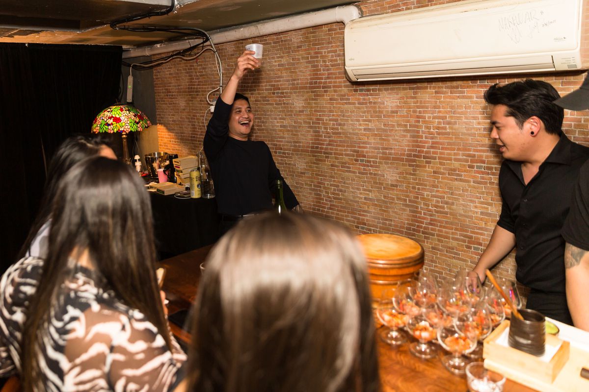 Chef&nbsp;Atip “Palm” Tangjantuk stands at the corner of the bar, toasting with a plastic cup of beer