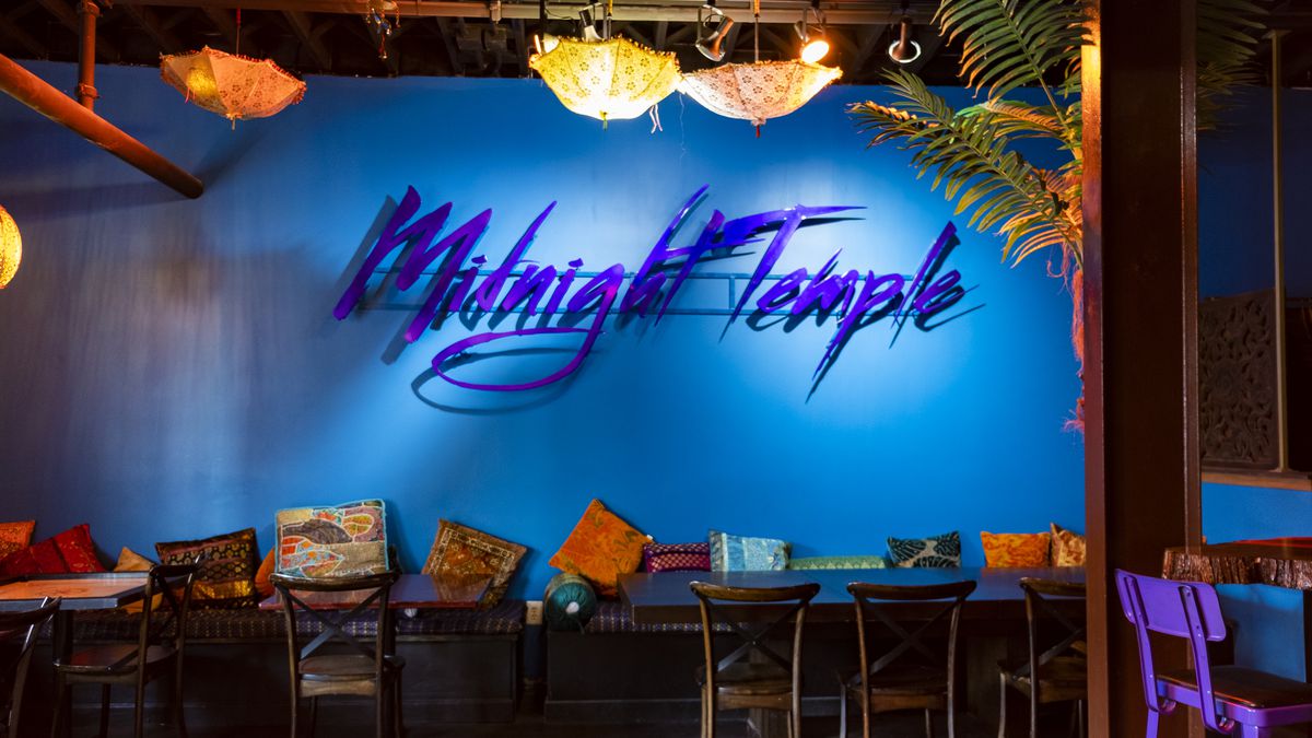 A blue wall with a sign in purple that reads Midnight Temple, accent pillows, seating on May 31, 2023 at Midnight Temple Located in Easter Market in Detroit, Michigan.