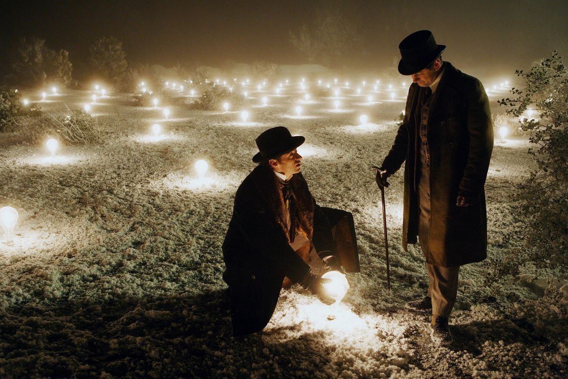 a man holds a glowing orb in The Prestige, next to another man in the snow