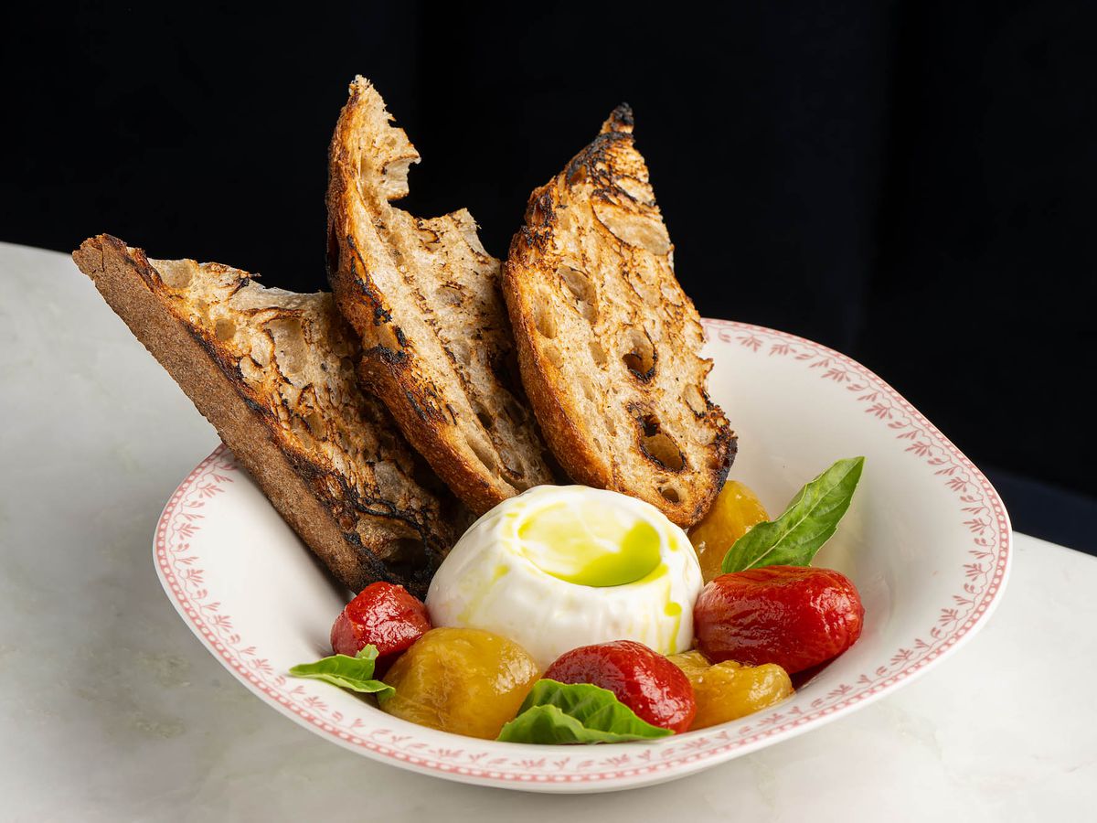 A bowl of burrata with tomatoes and grilled bread at Dante Beverly Hills.