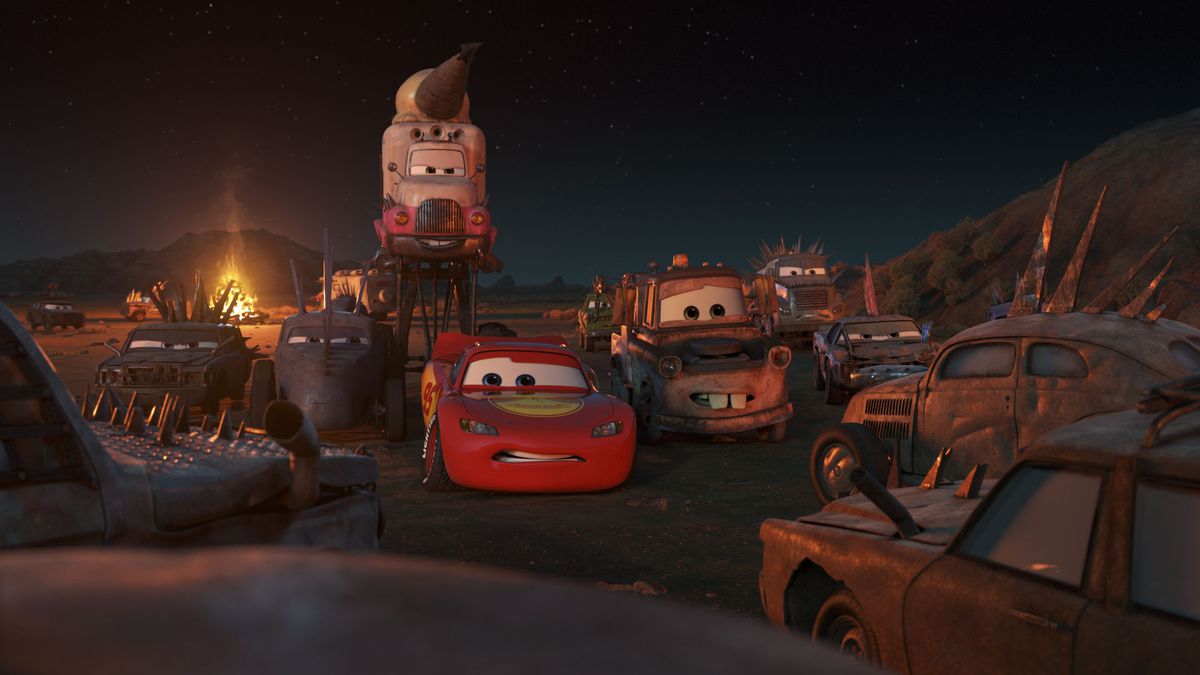 a screenshot from Cars on the Road. lightning mcqueen, a red race car, and mater, a rusty tow truck, cower while surrounded by grungy and aggressive cars wearing spikes. it is night and the light comes from various torches.