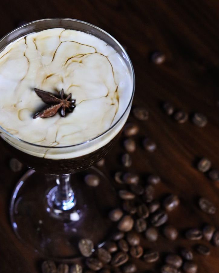 An overhead shot of a frothy espresso martini surrounded by coffee beans