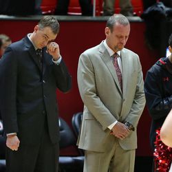 Assistant Phil Cullen, left,  and Utah Utes head coach Larry Krystkowiak bow their heads during a moment of silence before the game for the father of assistant coach Andy Hill, Rick Hill, who the Utes dedicated the season to in support of his battle against cancer, which he died of yesterday, as the University of Utah plays Cal in PAC 12 men's basketball action Sunday, Feb. 15, 2015, in Salt Lake City.  
