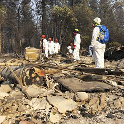 File - In this Nov. 18, 2018 file photo, volunteer members of an El Dorado County search and rescue team search the ruins of a home, looking for human remains, in Paradise, Calif., following a wildfire. Authorities have deployed a powerful tool to aid in their race to identify the remains of 77 bodies burned in the deadly wildfire that ripped through Northern California: Rapid DNA testing that produces results in just two hours. But the technology that can match DNA to bone fragments in as little as two hours is only as effective as the numbers of people who show up to give a sample, and so far there are not nearly enough volunteers. (AP Photo/Sudhin Thanawala, File)