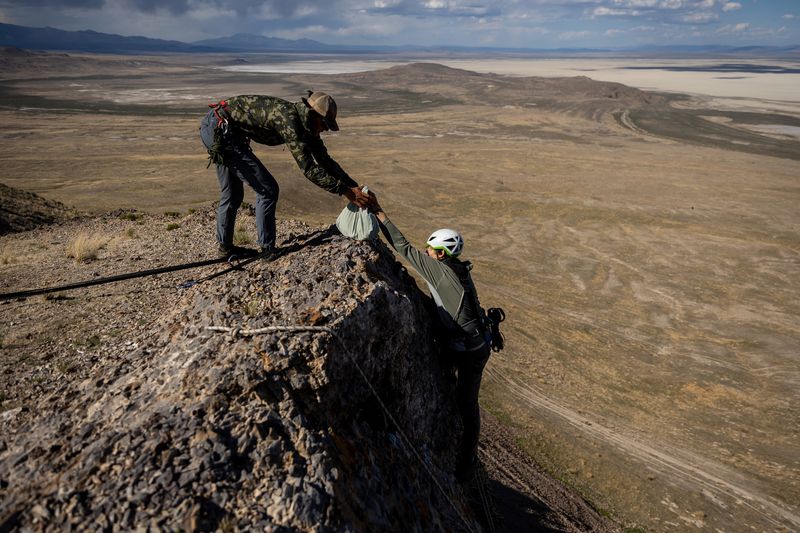 Hawkwatch International research associate Dustin Maloney, right, hands a bagged golden eagle nestling to field biologist Jayden Skelly after Maloney removed it from its nest on a cliff in a remote area of Box Elder County on Wednesday, May 19, 2021.