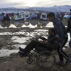 A migrant in a wheelchair is pushed across a flooded field at the northern Greek border station of Idomeni, Tuesday, March 8, 2016. Up to 14,000 people are stranded on the outskirts of the village of Idomeni, with more than 36,000 in total across Greece, as EU leaders who held a summit with Turkey on Monday said they hoped they had reached the outlines of a possible deal with Ankara to return thousands of migrants to Turkey. 