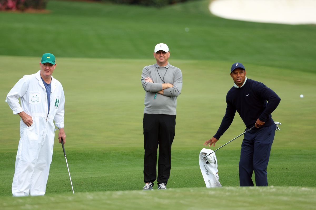 Tiger Woods of the United States warms up on the range as caddie Joe LaCava and Rob McNamara, Executive Vice President at TGR, look on during a practice round prior to the Masters at Augusta National Golf Club on April 05, 2022 in Augusta, Georgia.