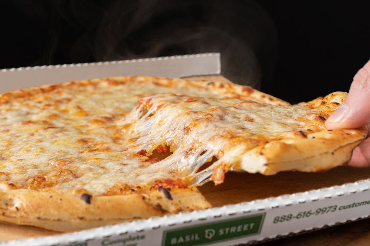 A cheese pizza in a cardboard box with cheese pull