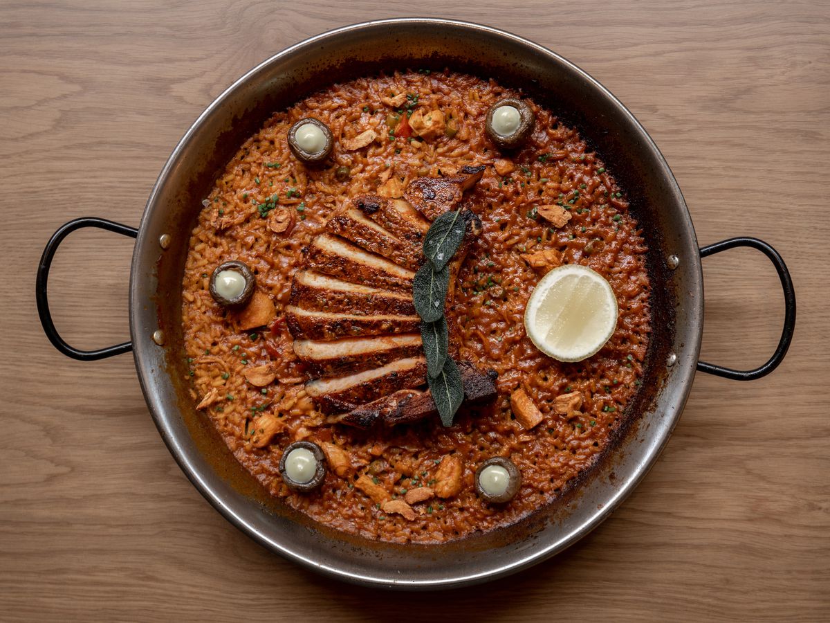 An overhead shot of sliced pork with fried green sage on paella at the new Telèferic.