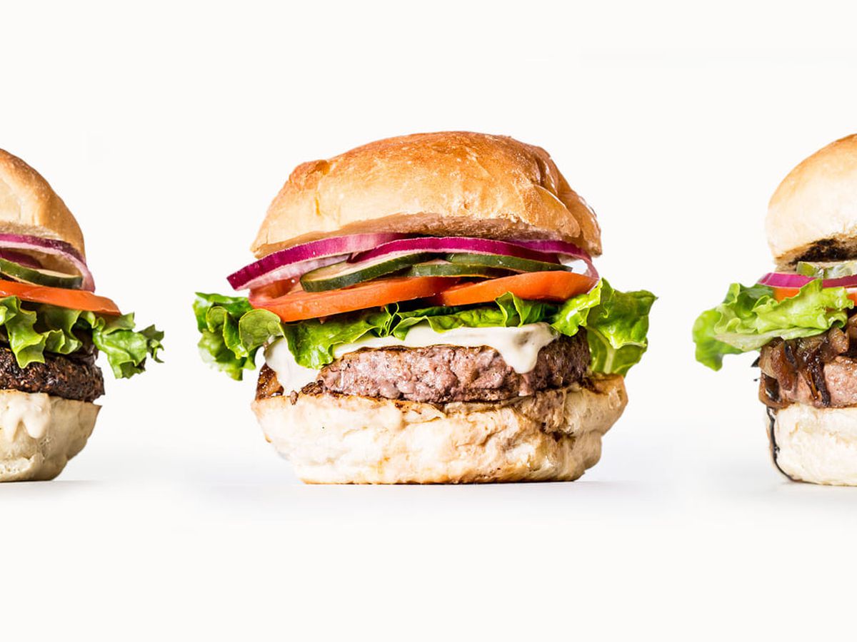 Three burgers sit in a line at Dick’s Primal Burger