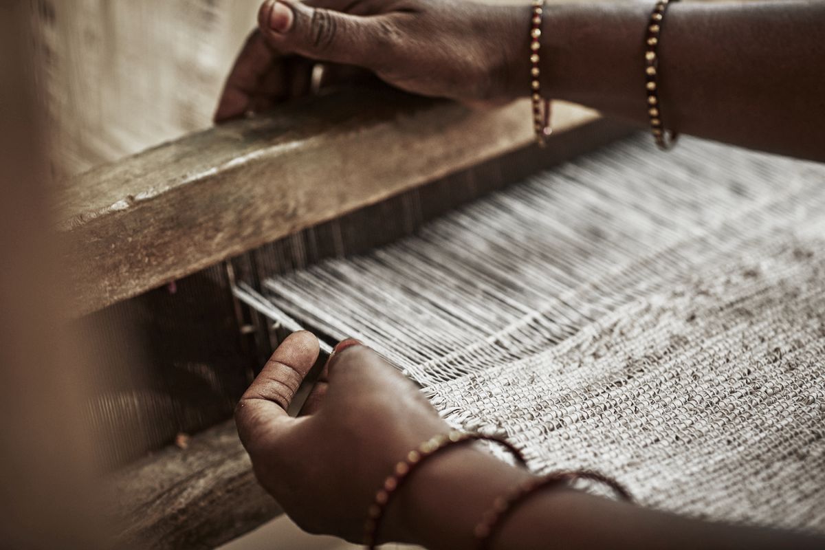 Woman weaving rug on loom.