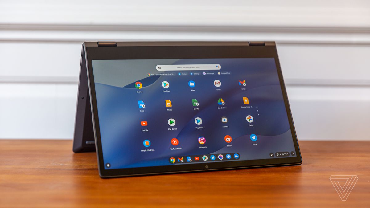 The Lenovo Flex 5 Chromebook in tent mode, angled to the right. The screen displays a grid of Chrome OS apps on a blue wavy background.