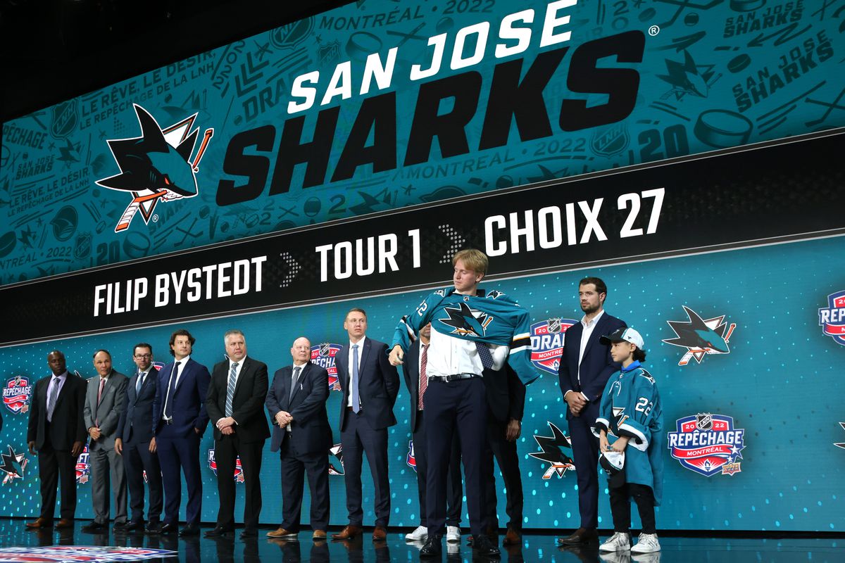 Filip Bystedt puts on a jersey onstage after being selected 27th overall by the San Jose Sharks during the first round of the 2022 Upper Deck NHL Draft at Bell Centre on July 07, 2022 in Montreal, Quebec.
