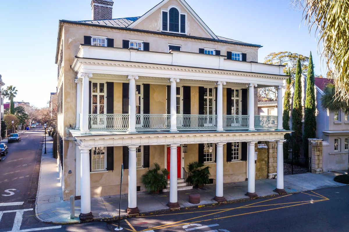 Three-story colonial home with two-story portico on corner lot. 