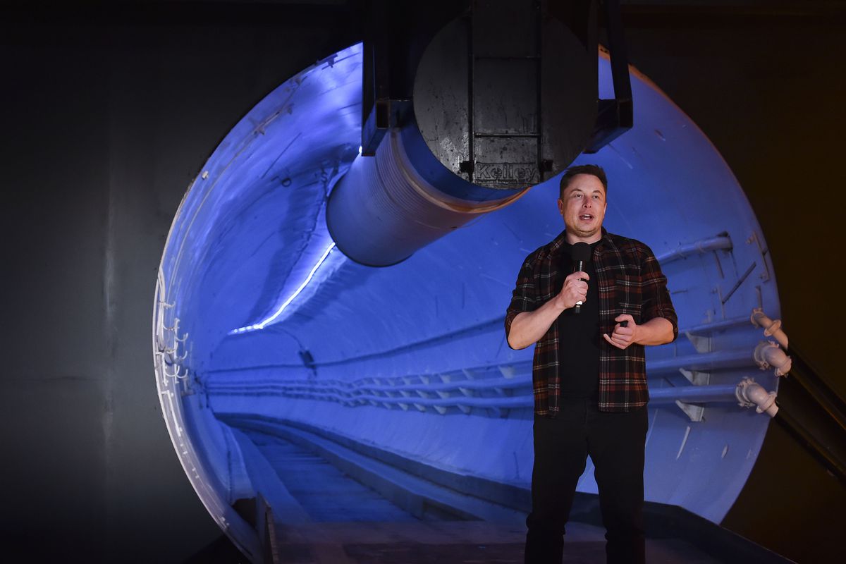 Elon Musk standing at the entrance to a car tunnel.