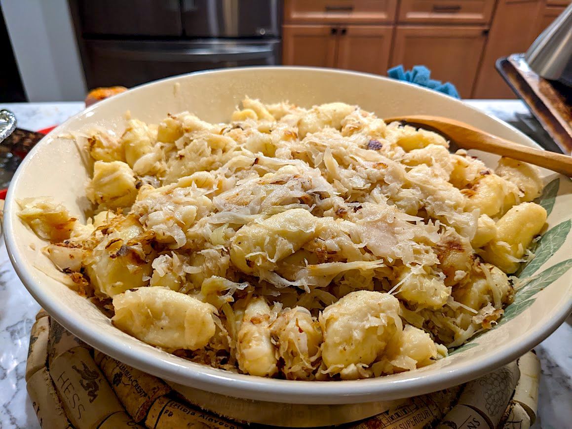 A large bowl of haluski topped with lots of onions.