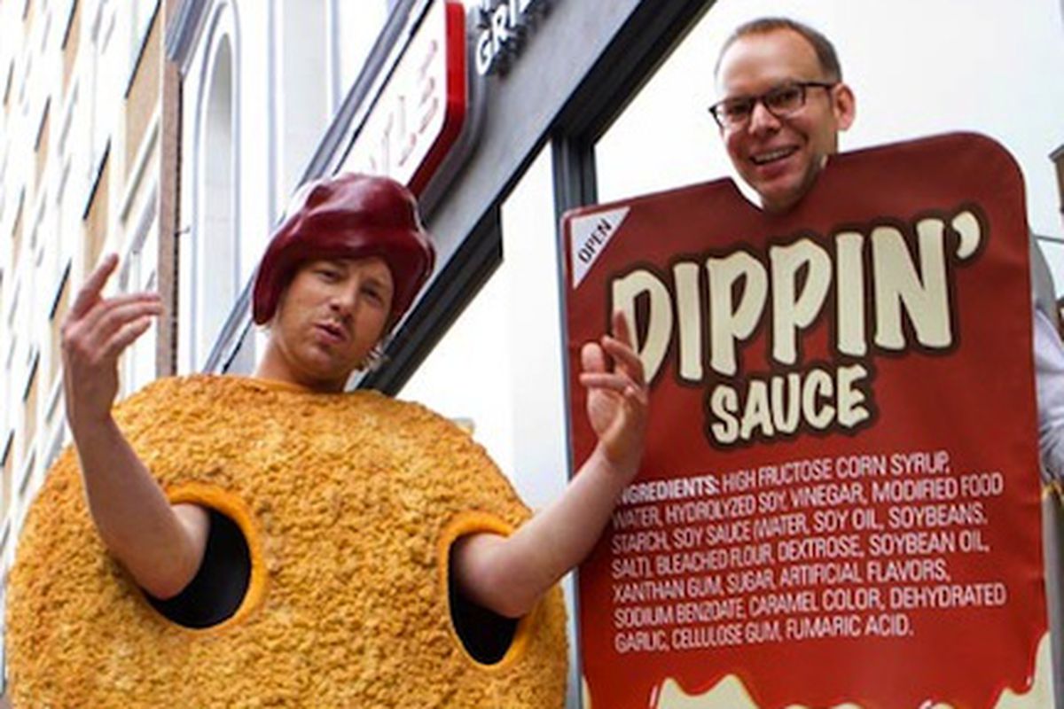 Jamie Oliver, dressed as a chicken nugget, doing chicken nugget gang signs. Presumably he dunked his head into Chipotle CEO Steve Ellis' Dippin' Sauce torso? 