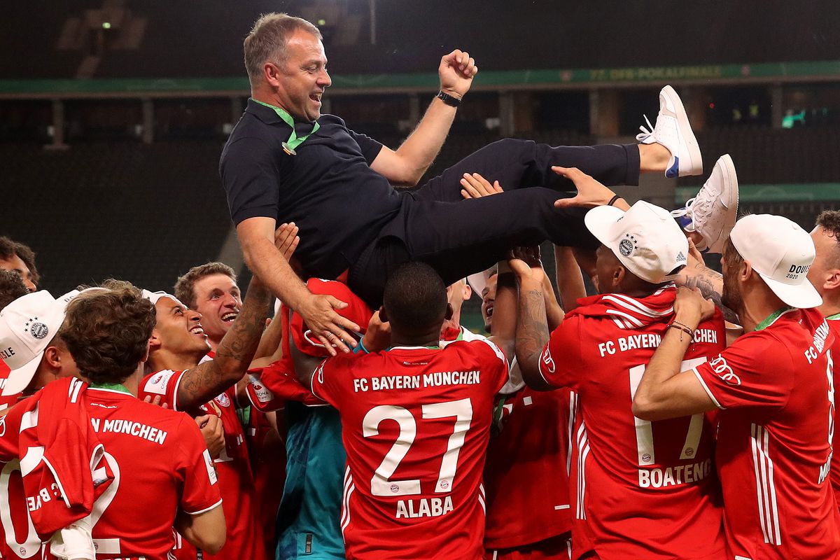 Players of FC Bayern Muenchen throw head coach Hansi Flick in the air after winning the DFB Cup