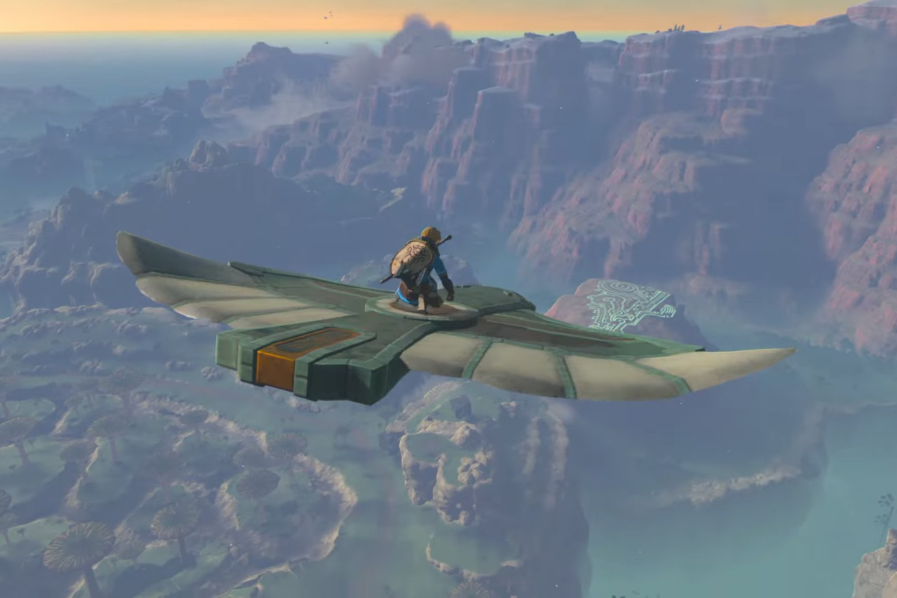 In a screenshot from The Legend of Zelda: Tears of the Kingdom, Link crouches on a stone bird that is flying in the air over Hyrule.