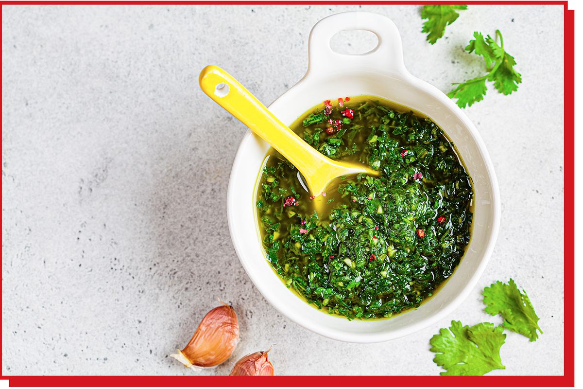 Finely chopped green herbs in olive oil in a ramekin with ceramic spoon.
