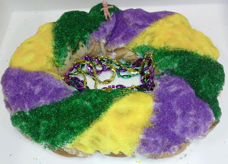 A round cake with a hole in the middle with segments of yellow, green, and purple colorings.