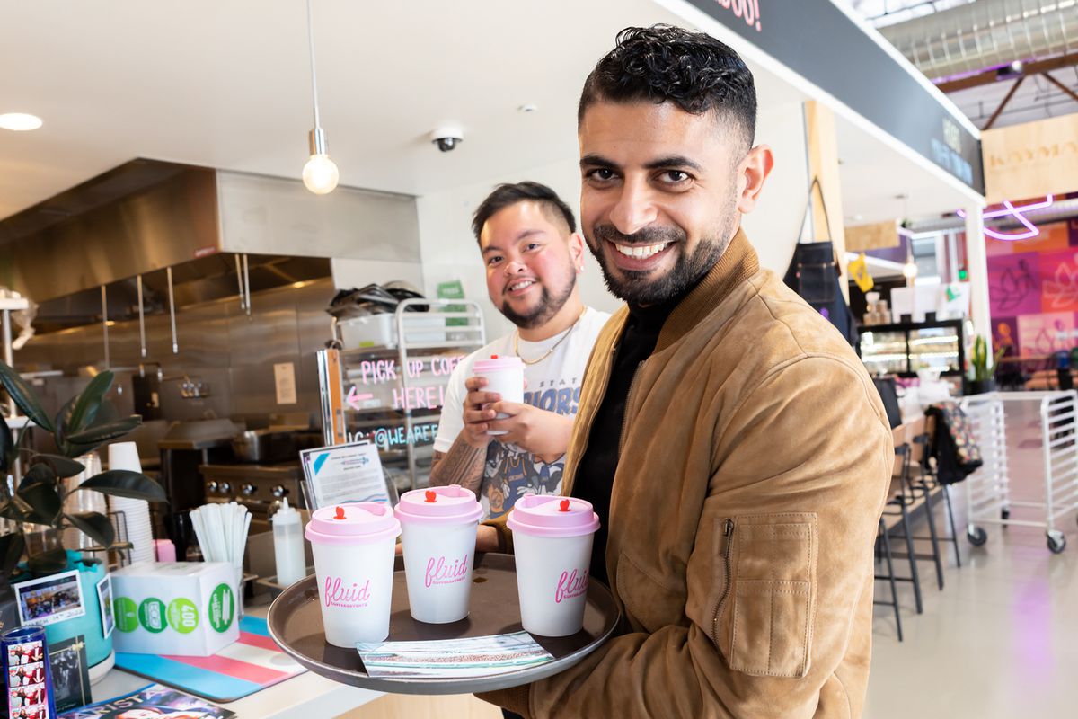 Two people with a tray of pink coffee cups.
