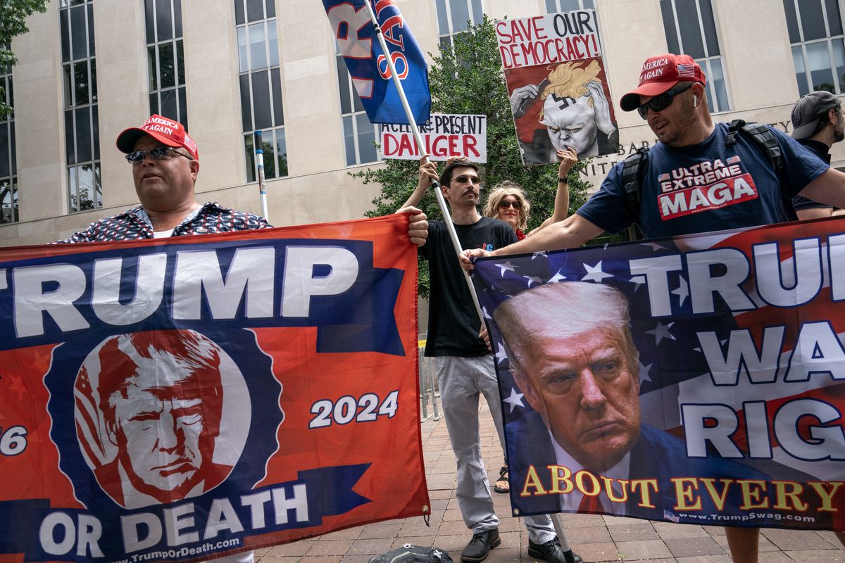 Trump supporters carry flags that read “Trump or death 2024” and “Trump was right about everything.”