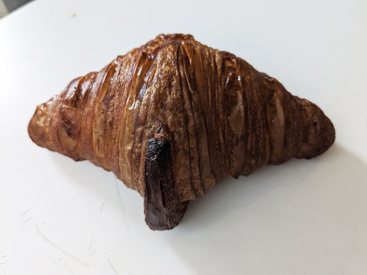 A very brown and slightly small croissant with a burned nose.