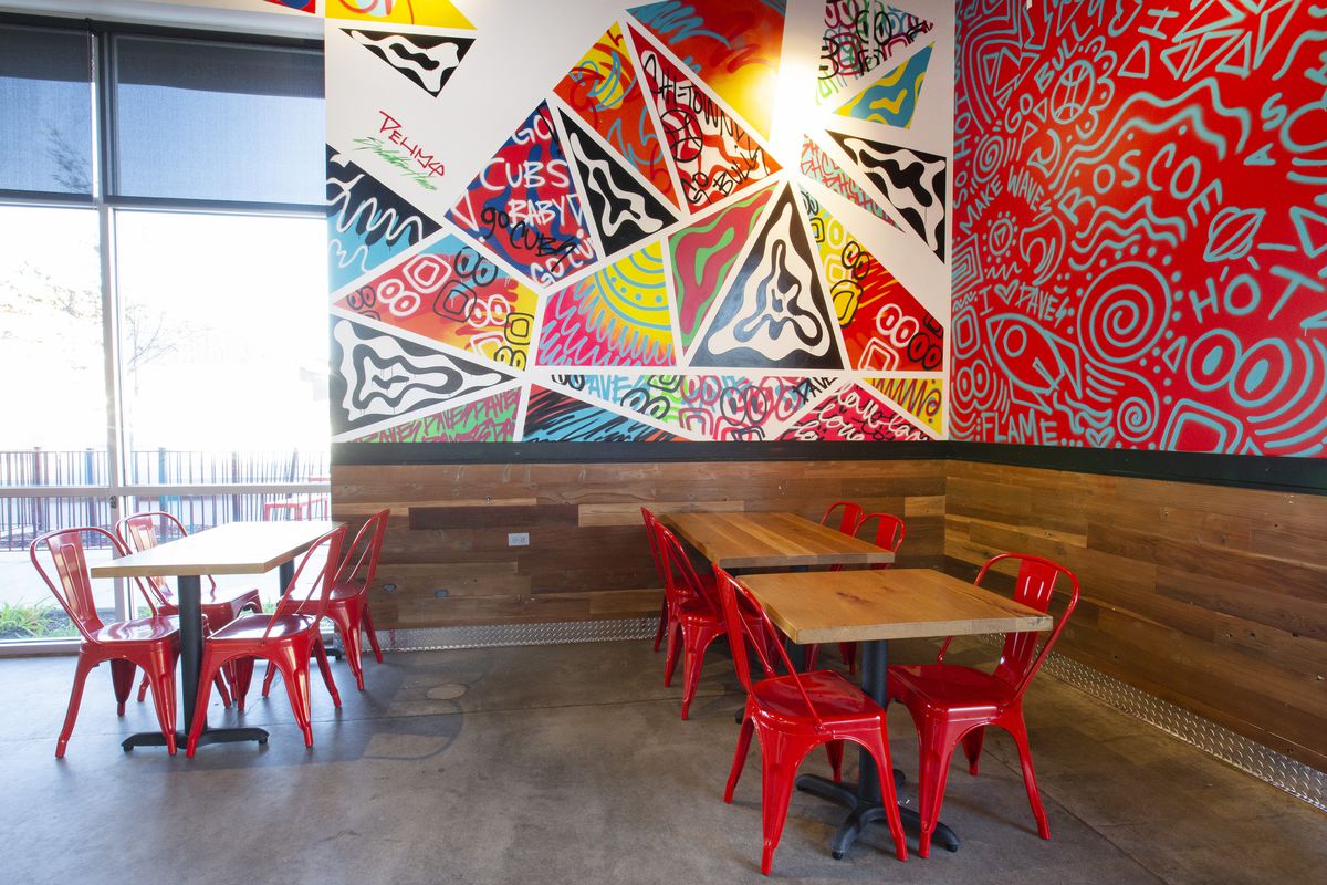 Two colorful geometric wall murals inside an otherwise spare restaurant space. 