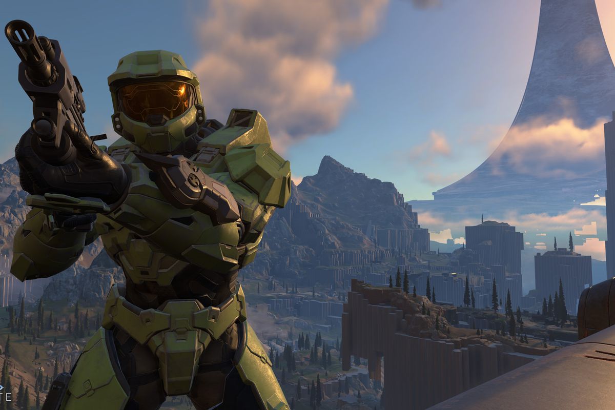 Master Chief aiming a gun while standing high up above a valley in Halo Infinite