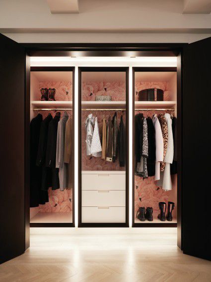 A coat room in an apartment which has pink walls.