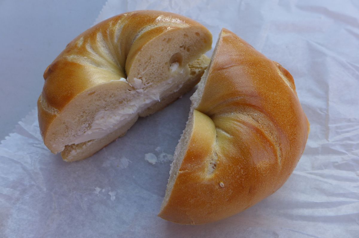 A bagel cut open to reveal white cream cheese.