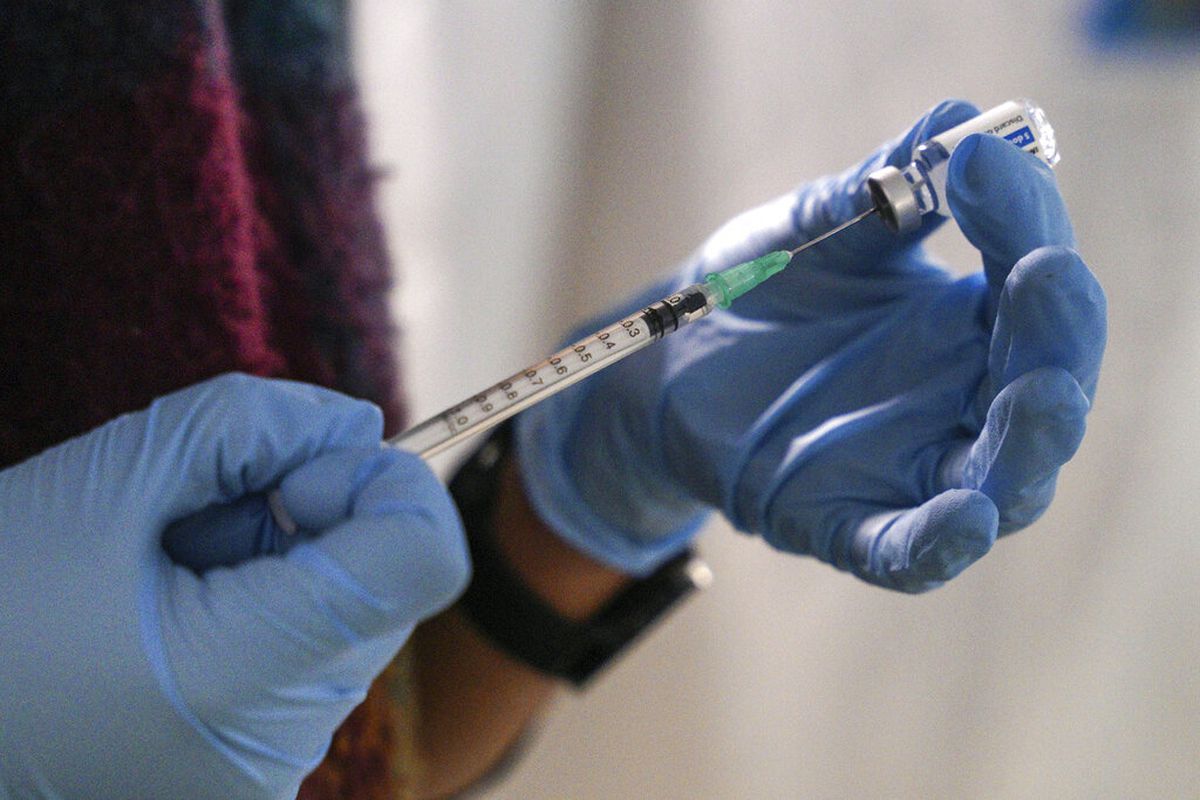 A staff member prepares a Johnson &amp; Johnson booster vaccine.