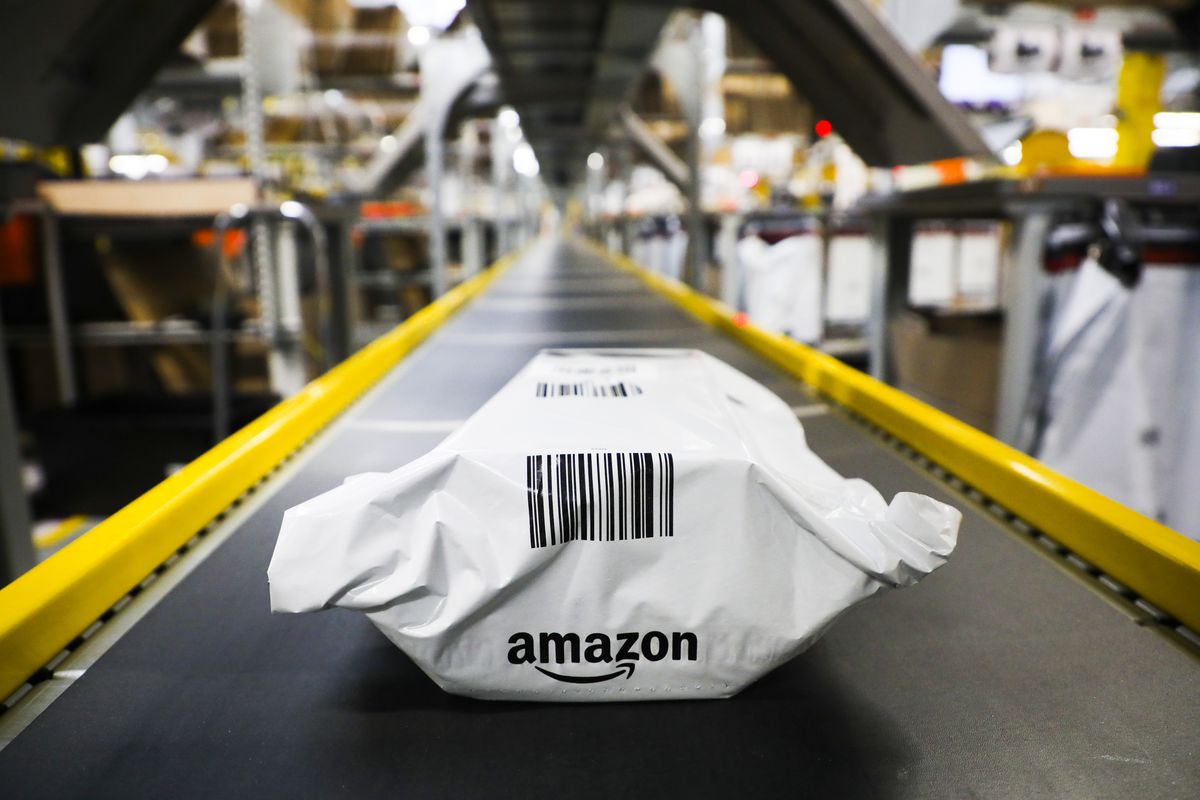 An Amazon package rides down a conveyor belt in a fulfillment center.