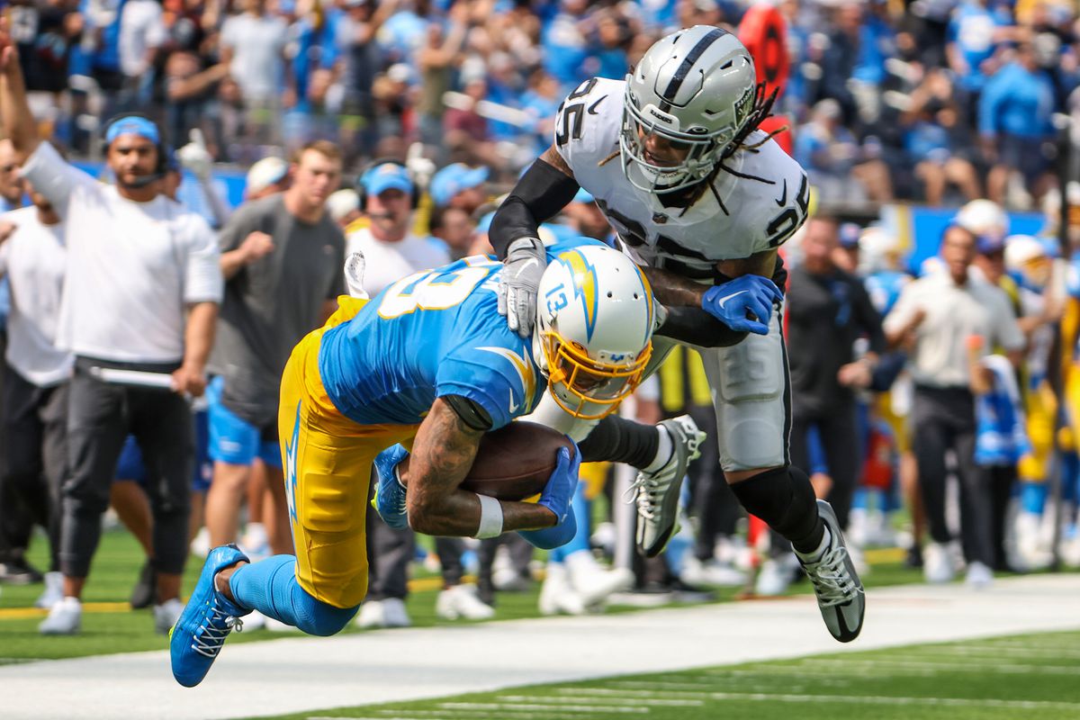 Los Angeles Chargers wide receiver Keenan Allen (13) is tackled by /Las Vegas Raiders safety Tre’von Moehrig (25) in the second quarter at SoFi Stadium.
