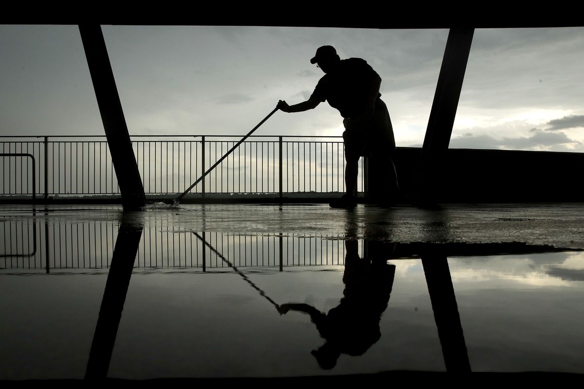 A worker sweeps rainwater into a drain on a concourse at Kauffman stadium after a severe storm passed through before a baseball game between the Kansas City Royals and the Cleveland Indians Tuesday, Aug. 28, 2018, in Kansas City, Mo.
